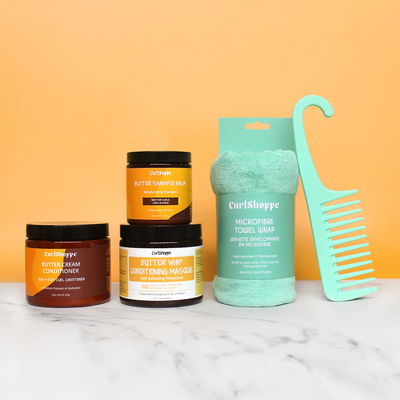 CurlShoppe hair care products with a teal microfiber towel wrap and turquoise comb on an orange background.