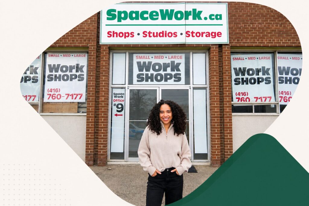Smiling woman stands outside a brick storefront with SpaceWork signage reading 'Shops • Studios • Storage' in bold letters.
