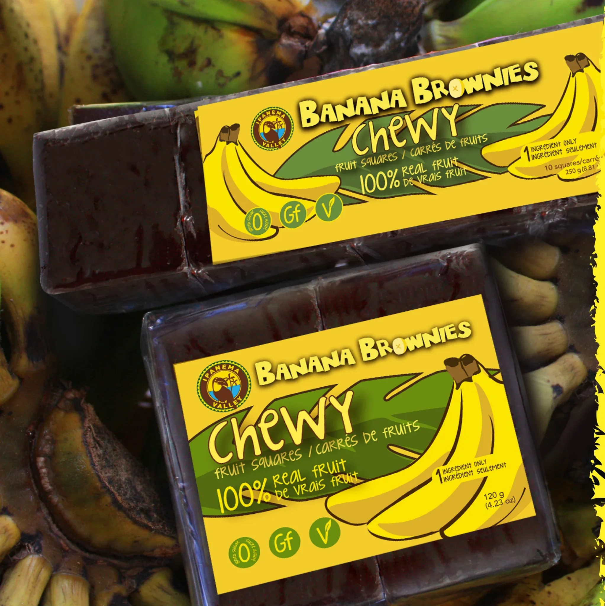 Bright yellow packaging reading Banana Brownies Chewy, with banana graphic and '100% real fruit' claim visible against chocolate bars and fruit background, close-up.